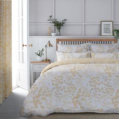 a bed with yellow and white comforters in a room next to a window,