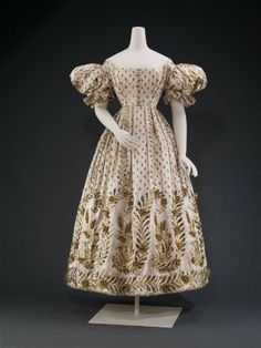 Ball dress, ca. 1825, French. White silk satin embroidered with plain and textured flat gilt wire, sprigs overall, flowers and wheat on sleeves and at skirt base, three dimensional flowers and wheat kernels over wire and net foundationsBall dress, ca. 1825, French. White silk satin embroidered with plain and textured flat gilt wire, sprigs overall, flowers and wheat on sleeves and at skirt base, three dimensional flowers and wheat kernels over wire and net foundations. Museum Of Fine Arts Boston, Era Fashion, Court Dresses