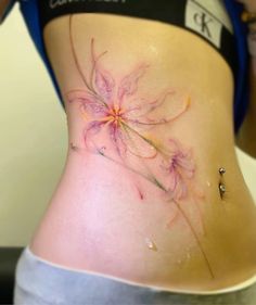 a woman's stomach with a flower tattoo on her side and the bottom part of her belly