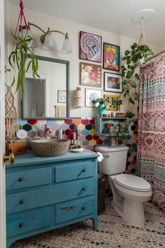 a bathroom with a toilet, sink and colorful rugs on the wall above it