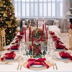 a table set for christmas dinner with red napkins