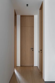 an empty room with two wooden doors and white walls on either side of the door