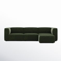 a green couch sitting on top of a white floor next to a chair and ottoman