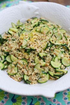 a white bowl filled with cucumbers and grains