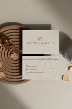 two business cards sitting on top of a wooden plate next to some gold foil coins