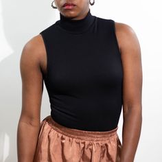 Layer her up or bare your arms. A simple staple with a little bit of texture. Sleeveless ribbed seamless top in black. 92% Nylon 8% Spandex One-Size Solid High Neck Ribbed Tank Top, Solid Ribbed High Neck Tank Top, Ribbed Turtleneck Tank Top, Chic Solid Color Sleeveless Mock Neck Top, Chic Sleeveless Mock Neck Top In Solid Color, Trendy High Neck High Stretch Tank Top, Ribbed High Neck Tank Top, Stretch Mock Neck Top For Night Out, Chic High Neck Ribbed Tank Top