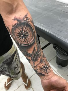 a man's arm with a compass tattoo on it