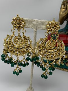 These gorgeous Kundan earrings are featured with amazing combination of Kundan work and green beads.  Made on brass base metal and then gold plated. Approximate length of the earrings is 4 inches and width is ~2inches We carefully inspect each piece before shipping and package in cotton padded box to ensure it arrives safely. All orders are shipped free using USPS, Fedex or UPS.  Please contact with-in 3 days of delivery if you are not satisfied and would like to exchange. Sorry, no returns. Connect with us on Facebook at www.facebook.com/aashi.us to checkout our more designs and see what our customers say about us. Feel free to contact us here on Etsy or at Facebook if you have any question. Brass Bridal Earrings For Festivals And Celebrations, Festive Brass Chandbalis For Celebration, Handmade Emerald Jewelry For Festive Occasion, Festive Celebration Brass Chandbalis, Bollywood Style Brass Chandbalis As Gift, Festive Stone Work Beaded Earrings, Traditional Green Beaded Earrings For Party, Traditional Green Beaded Party Earrings, Brass Chandbali Bridal Earrings