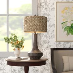 a lamp sitting on top of a wooden table next to a vase filled with flowers