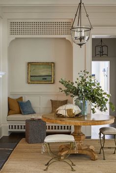 a living room filled with furniture and a chandelier hanging from the ceiling over a wooden table