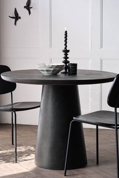 a round table with two chairs and a candle on it in front of a white wall