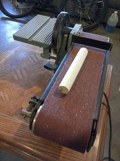 a machine that is sitting on top of a wooden table with a roll of paper in front of it