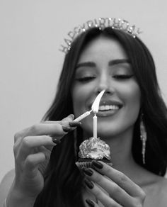 a woman wearing a tiara holding a lit candle