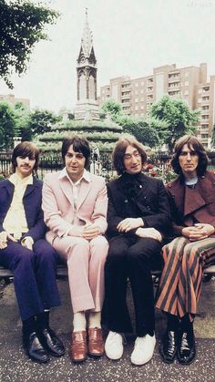 four people are sitting on a bench in the park