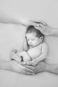 a black and white photo of a baby being held by his parents hands in the air