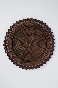 a brown woven placemat on a white surface with an intricate design in the center