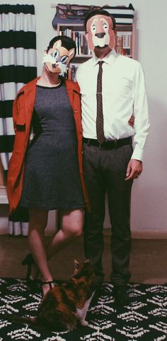 a man and woman standing next to each other in front of a cat on the floor