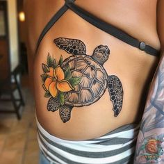 a woman with a tattoo on her stomach has a turtle and flower tattooed on it