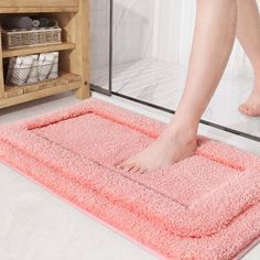 a person standing on a pink rug in a bathroom