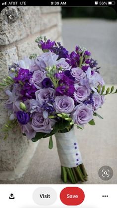 a bouquet of purple flowers sitting on top of a stone wall