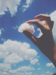 someone is flying a kite in the blue sky with white clouds above their head on a sunny day