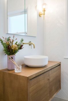 a bathroom with a sink, mirror and vase on the counter in front of it