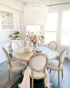 a dining room table with white chairs and a chandelier hanging from the ceiling