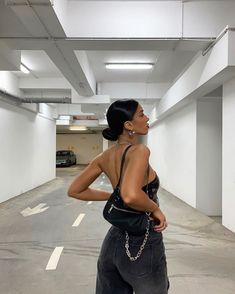 a woman standing in an empty parking garage with her back to the camera and looking up