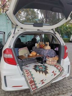 the back end of a white car with food and drinks in it's trunk