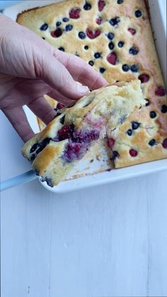 a person picking up a piece of blueberry cake