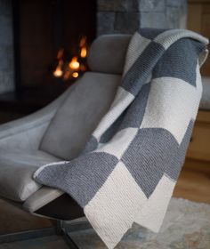 a gray and white checkered blanket sitting on top of a chair in front of a fireplace