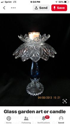 a glass candle holder with a lit candle in the center on a black background,