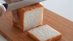 someone is slicing bread with a knife on a cutting board and it looks like they are going to eat something