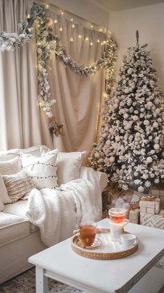 a living room decorated for christmas with a white tree and presents on the coffee table