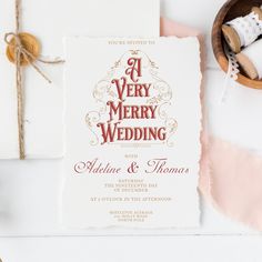 a very merry wedding with red and gold lettering on white paper next to a pair of shoes