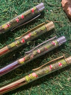 four pens are lined up on the ground with green grass and flowers painted on them