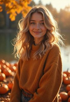 a woman sitting on the ground with pumpkins in front of her and smiling at the camera