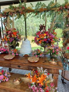 a table topped with a white cake and lots of flowers on top of wooden tables