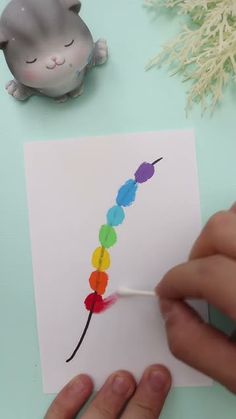 a person is painting a rainbow colored caterpillar on a piece of white paper