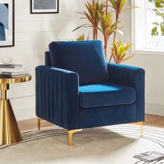 a blue chair sitting in a living room next to a table and potted plant