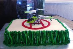 a cake decorated with grass and a helicopter on top