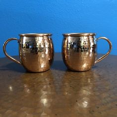 two shiny metal cups sitting on top of a table