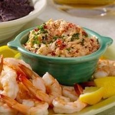 a plate with shrimp, rice and lemon wedges on it next to other dishes