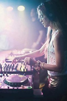 a woman in headphones is mixing music on a turntable at a club or nightclub