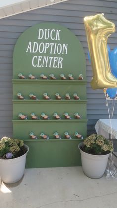 there is a sign that says duck adoption center and two potted plants next to it