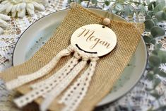 a plate with a tag on it sitting on a table next to flowers and greenery