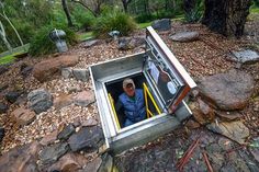 a man sitting in an open box surrounded by rocks