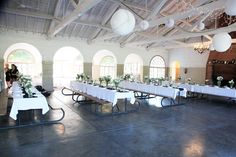 a long table is set up with white linens and greenery for an event