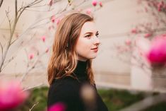 a woman standing in front of a tree with pink flowers