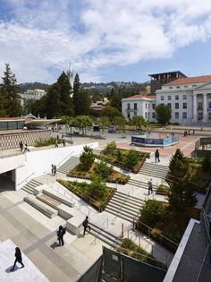 people are walking around in an open area with stairs and trees on the other side